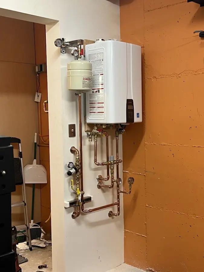 Plumbing technician inspecting water heater connections in Pewaukee